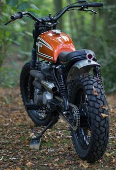 an orange and black motorcycle parked in the woods