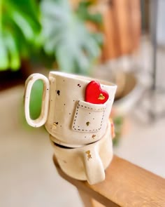 a coffee cup with a red heart in it sitting on top of a wooden table