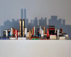 several books are stacked on top of each other in front of a cityscape