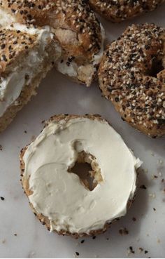 bagels with cream cheese and sprinkles are on a white surface next to each other