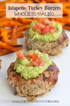 two burgers with guacamole and tomatoes on top