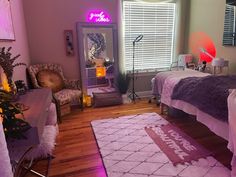 a bedroom decorated in pink and purple with a bed, desk, chair, mirror and lights