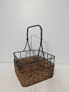 a basket that is sitting on the floor in front of a white wall with a black handle