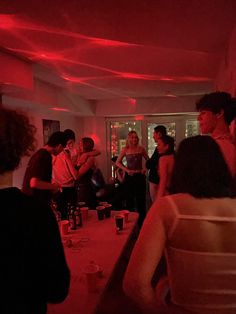 a group of people standing in a room with red lights on the ceiling and walls