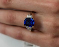 a close up of a person's hand holding a ring with a blue stone