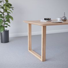 a wooden table with a plant in the corner