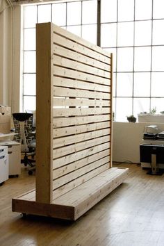 a wooden partition in the middle of a room with lots of windows and wood flooring