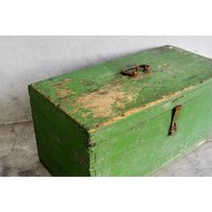 an old green box is sitting on the floor next to a white wall and cement floor