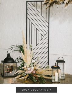 an arrangement of flowers and candles on the floor in front of a white brick wall