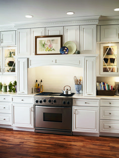 a kitchen with white cabinets and stainless steel stove top oven in the center of the room