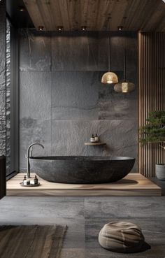 a large black bathtub sitting in the middle of a bathroom next to a plant