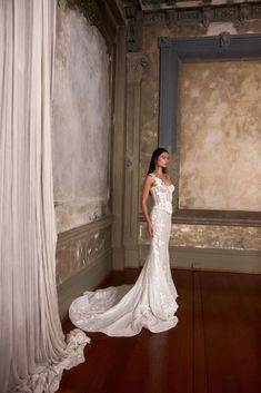 a woman in a white wedding dress standing on a wooden floor next to a window