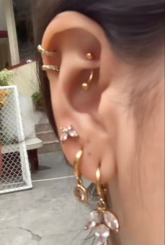 a woman wearing gold ear piercings with pearls on her left ear and behind the ear