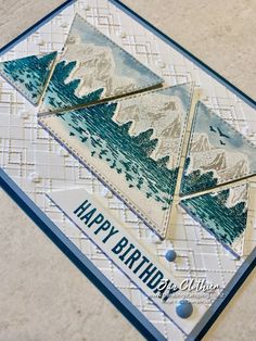 a handmade birthday card with mountains and trees on the front, in blue and white