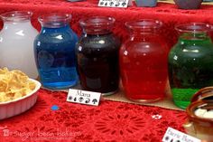 there are many different colored jars on the table with food in bowls next to them