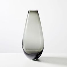 a glass vase sitting on top of a white table next to a black and gray object