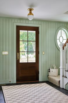 an entryway with green walls and white rug on the floor next to a wooden door