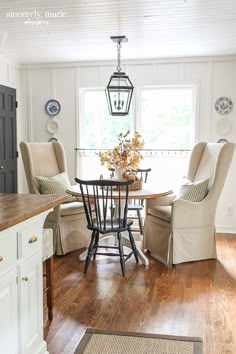 a dining room table with chairs and a lamp hanging from the ceiling in front of a window