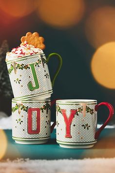 two coffee mugs decorated with the word joy and a teddy bear on top are sitting next to each other