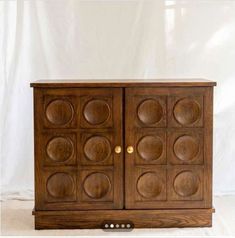 a wooden cabinet with many circles on the front and sides, sitting against a white backdrop