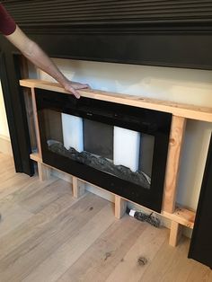 a person reaching for candles in front of a fireplace