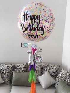 a happy birthday balloon sitting on top of a couch with the number twenty five in front of it