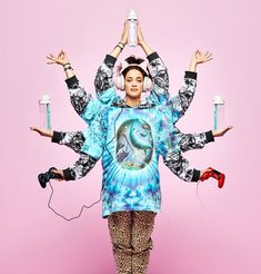 a woman standing in front of a pink background wearing headphones and holding two water bottles