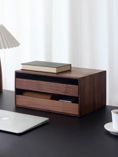 a laptop computer sitting on top of a desk next to a wooden box with books