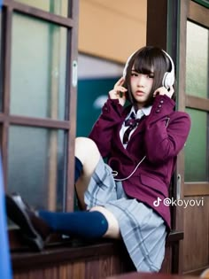 a young woman sitting on top of a window sill while listening to headphones