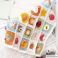 a crocheted blanket with animals on it sitting on top of a white bed