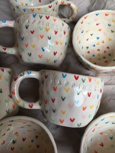 a group of ceramic cups and saucers with hearts painted all over them on a sheet