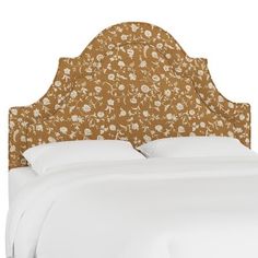 an upholstered headboard with white linens and floral print on the top