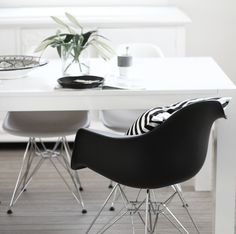 a white table with black chairs and a plant