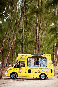 a yellow food truck parked in front of trees