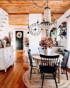 a dining room table with four chairs and a clock hanging from the ceiling above it