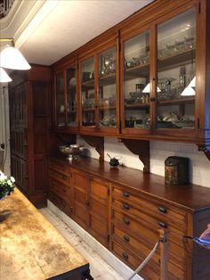 an old fashioned kitchen with wooden cabinets and glassware on the counter top, along with other antique items