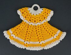 a yellow and white crocheted dress on a gray surface