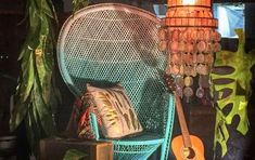 a green chair with a guitar on it next to a lamp and other items in the background