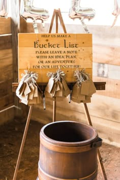 a wooden sign sitting on top of a barrel next to a metal bucket filled with paper