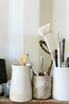 some pens, scissors and other items are sitting on a shelf next to each other