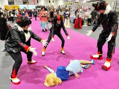 several people in costumes are performing on the pink carpet