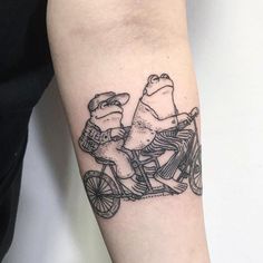 two people riding on a bike tattoo design on the left forearm and arm, both wearing hats