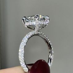 a close up of a person's hand holding an engagement ring with diamonds on it