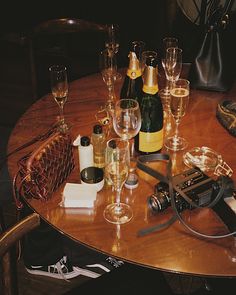 a table with wine glasses, champagne bottles and an old camera on it's side