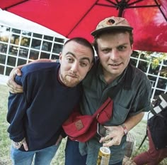 two men are hugging under an umbrella and posing for the camera with their arms around each other