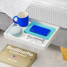 a bed side table with a blue laptop and glasses on it