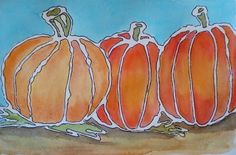 three orange pumpkins sitting on top of a blue and white paper sheet with watercolor paint