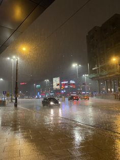 cars are driving down the street in the rain at night with lights shining on them