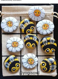 the bees are painted on rocks with white and yellow flowers