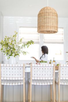 a woman sitting at a kitchen table in front of a potted plant on the counter